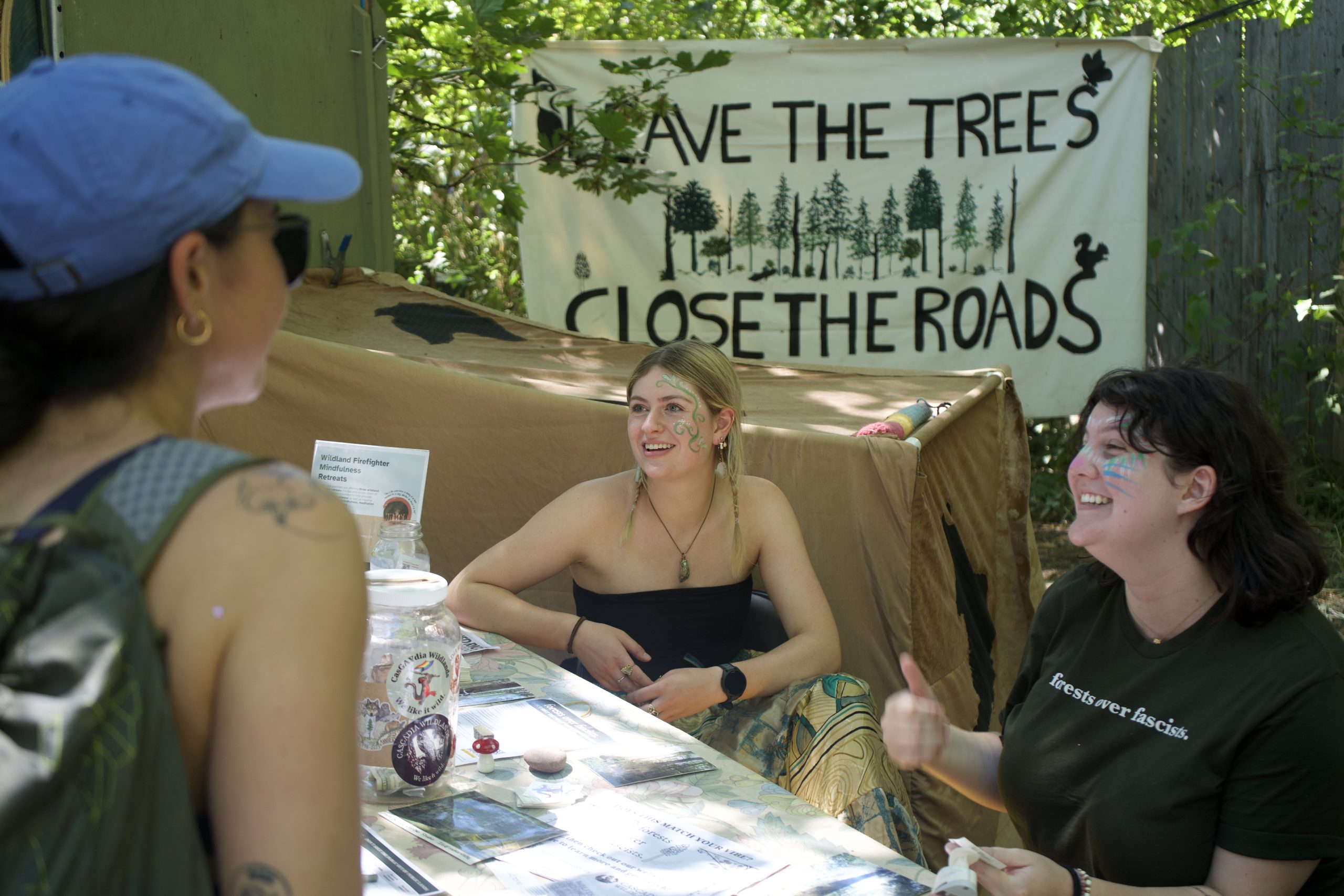 Two people sitting at a table enthusiastically talk to a person while sitting at a table.